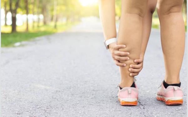 Runner holding calf and ankle in pain from a tendon injury